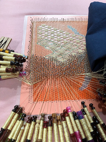 Bee bobbin lace project - picture of lace, bobbins, and cover cloth.