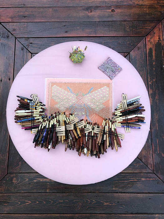 Bee bobbin lace project - overhead picture of the lace, bobbins, pins, and pin cushion. 