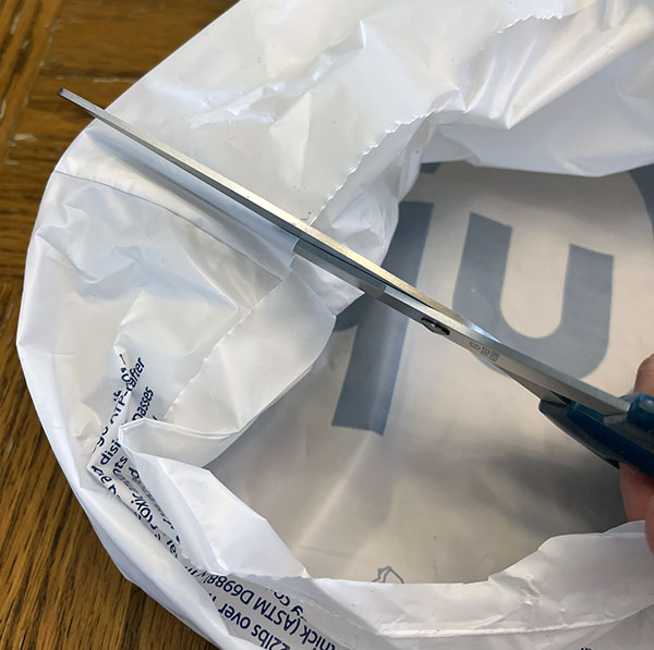 cutting on either side of the seam of the plastic bag