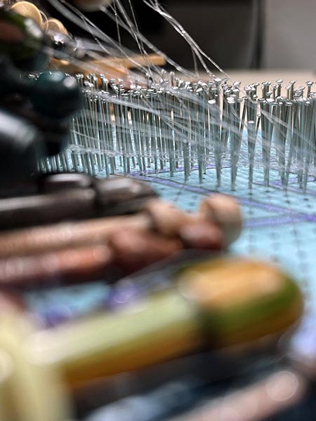 Pins in the bobbin lace pattern, bobbins, and some fishing line threads.