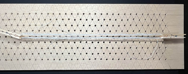 Steamed skein of thread drying on a peg board. 