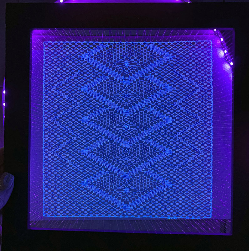 Final artwork glowing under blacklight, during a test fit into the shadowbox.