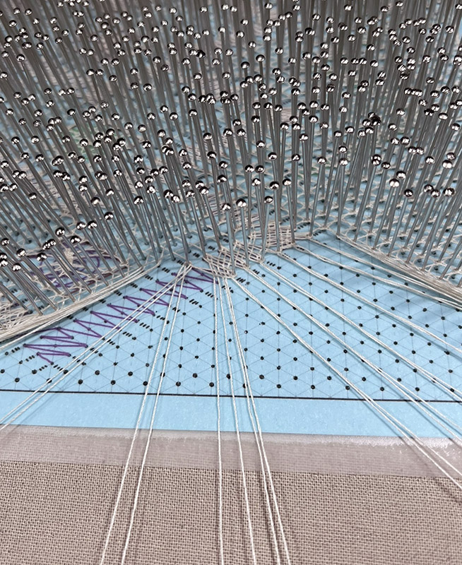 Final section of the lace in progress, showing thick cloth stitch trail nearing completion.