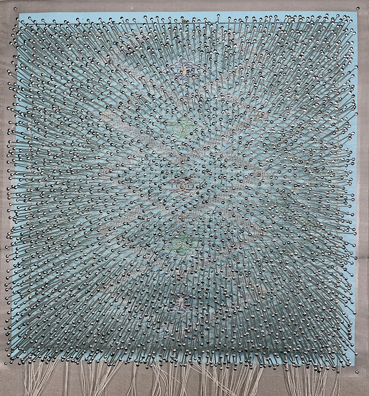 Finished lace partially revealed past pins.