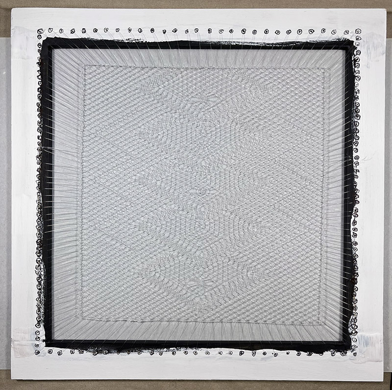 Finished lace sewn into a wooden frame, ready to be placed in the shadowbox.